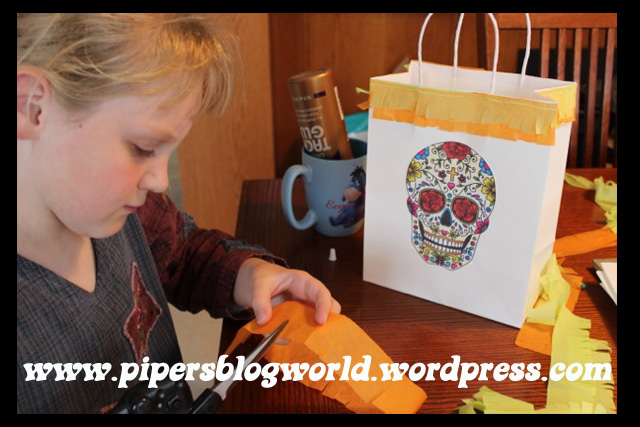 Piper made gift bags for the party guests by gluing crepe paper fringe and a sugar skull to each bag.